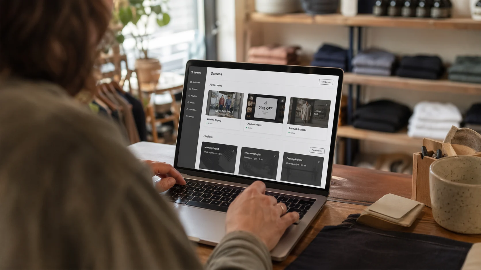 Majitel obchodu používá notebook ke správě playlistů digitální signage pro výlohu, pokladnu a produktové spotlighty